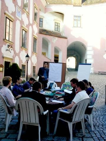 Teilnehmer der ersten Klausur sitzen im Innenhof von Schloss Drosendorf um einen Arbeitstisch