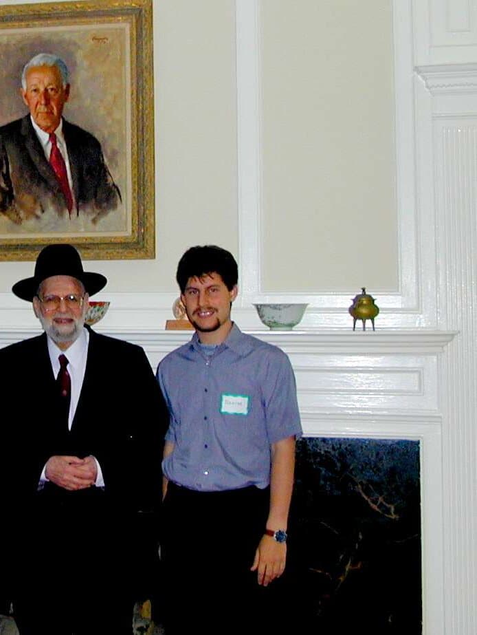 Israel M. Kirzner and Rahim Taghizadegan stand in front of a fireplace