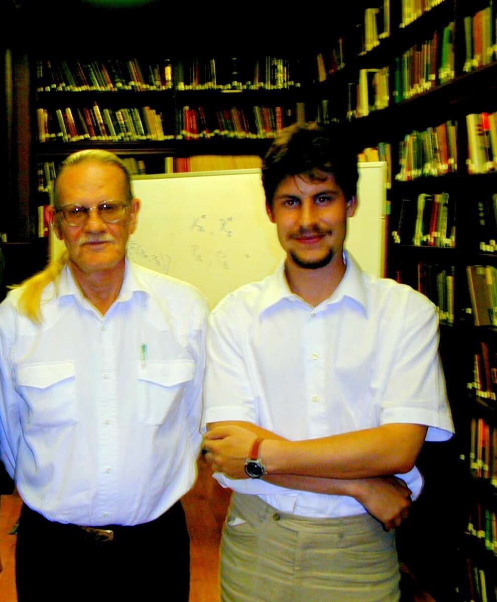 Rahim Taghizadegan steht in einer Bibliothek neben dem Ökonomen Vernon L. Smith