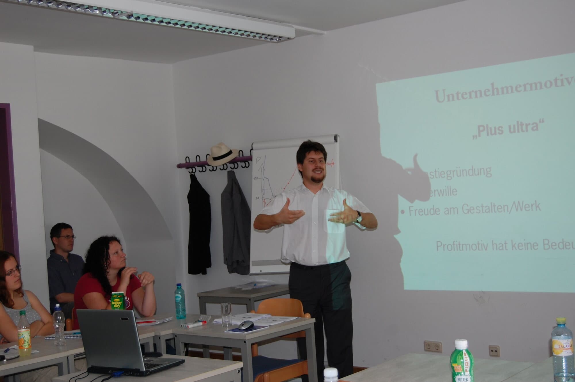 Rahim Taghizadegan lehrt vor einer Projektion über Unternehmermotive in einem Seminarraum der WU Wien