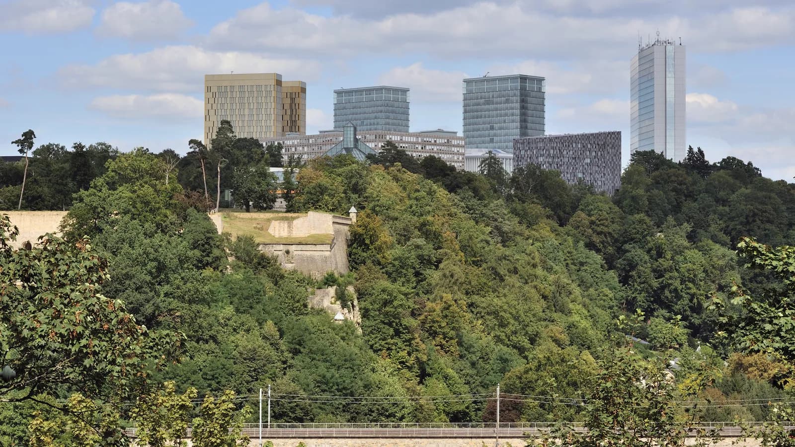 Las torres de oficinas de la meseta del Kirchberg se alzan sobre laderas boscosas, restos de la fortaleza y un viaducto ferroviario.