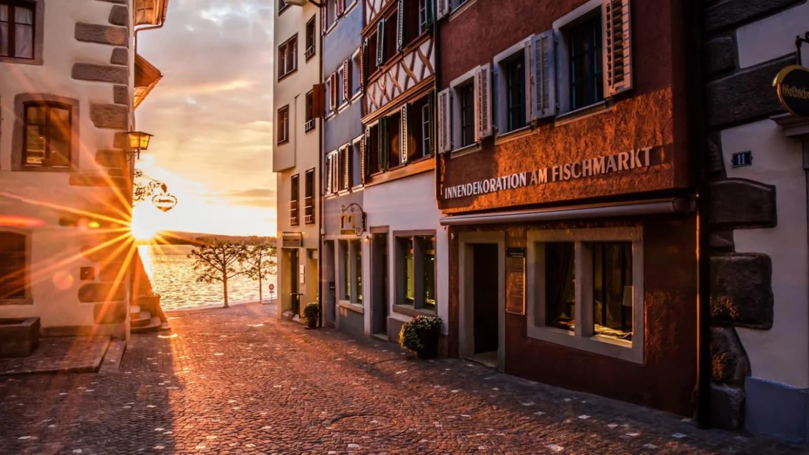 Abendlicht fällt durch eine Gasse der Zuger Altstadt auf den Zugersee.